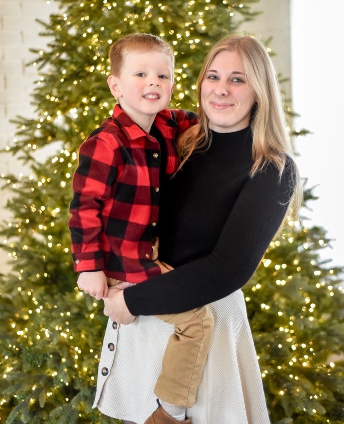 Left - child, right, - Morgan, annual fund coordinator for Freestore Foodbank. Standing in front of a tree with white lights. 